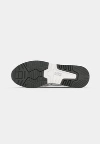 Shoe sole features a black rubber texture with deep tread patterns and white midsole accents. ASICS logo is embossed near the heel.