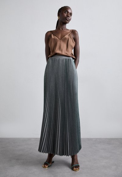 Hnedá saténová tielko s tenkými ramienkami, skombinované s plisovanou sukňou po zem v tmavozelenej farbe. Tento outfit sa vyznačuje hladkou textúrou a elegantným dizajnom.