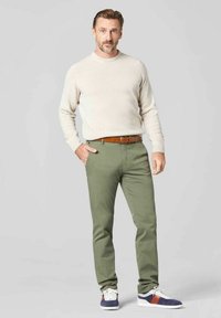 Beige Strickpullover, olivgrüne Hose, brauer Gürtel und grau-blaue Sneakers mit roten Akzenten. Lässiges Outfit mit tailliertem Schnitt.
