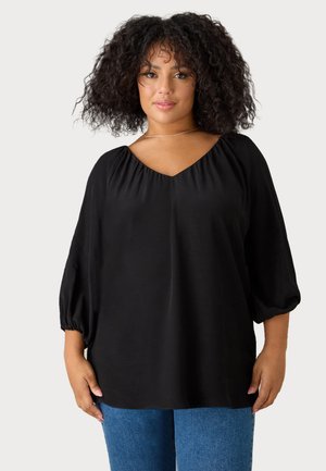 Blusa nera con scollo a V e dettagli arricciati sulle spalle, maniche puff a 3/4. Tessuto morbido con vestibilità rilassata, abbinata a denim blu.