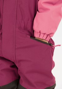 Fuchsia en roze buitensportpak met elastische manchetten, voorzien van een zijzak met rits. Gemaakt van textuurstof, geschikt voor actieve kleding.