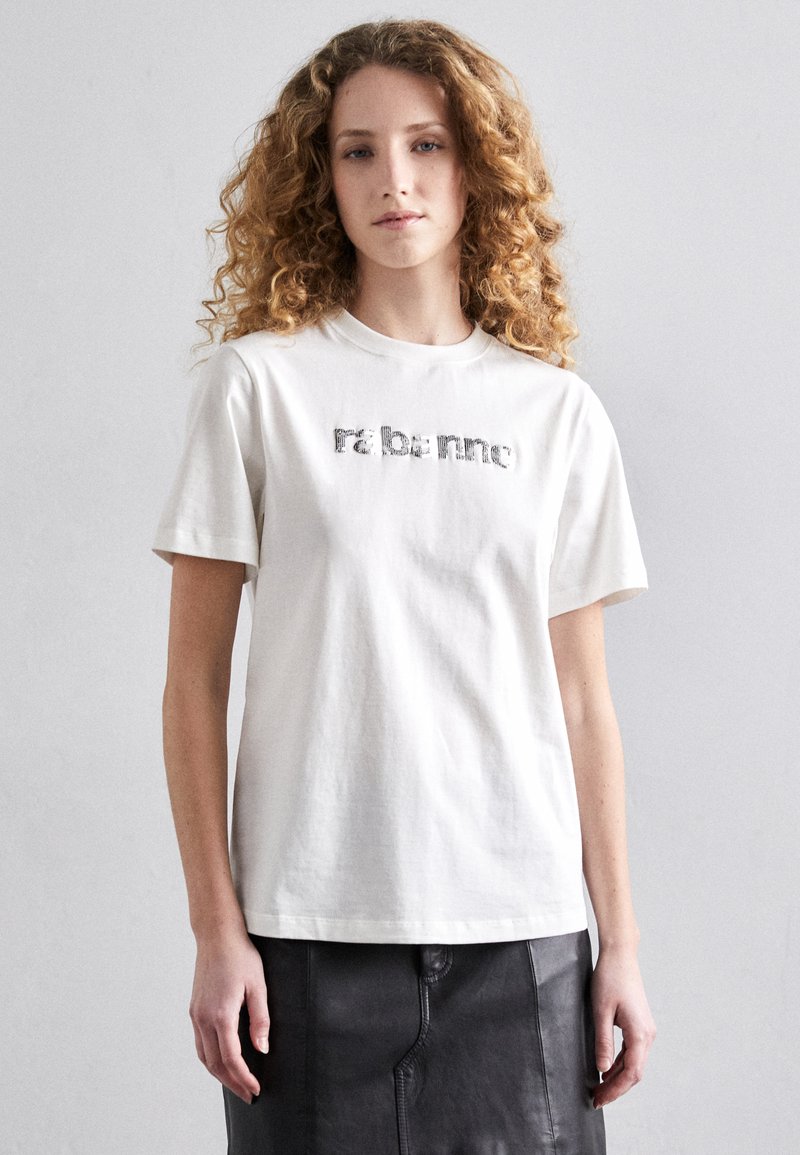 T-shirt en coton blanc avec un imprimé graphique texturé sur la poitrine, col rond et manches courtes. Design simple et coupe décontractée.