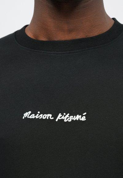Schwarzes Baumwoll-Sweatshirt mit Rundhalsausschnitt, das auf der Vorderseite mit weißem gesticktem Text "Maison Kitsuné" verziert ist. Glatte Textur mit einem schlichten Design.