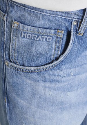 Primo piano della tasca di jeans in denim blu con cuciture gialle e nome del marchio "MORATO" ricamato sulla piccola tasca frontale.