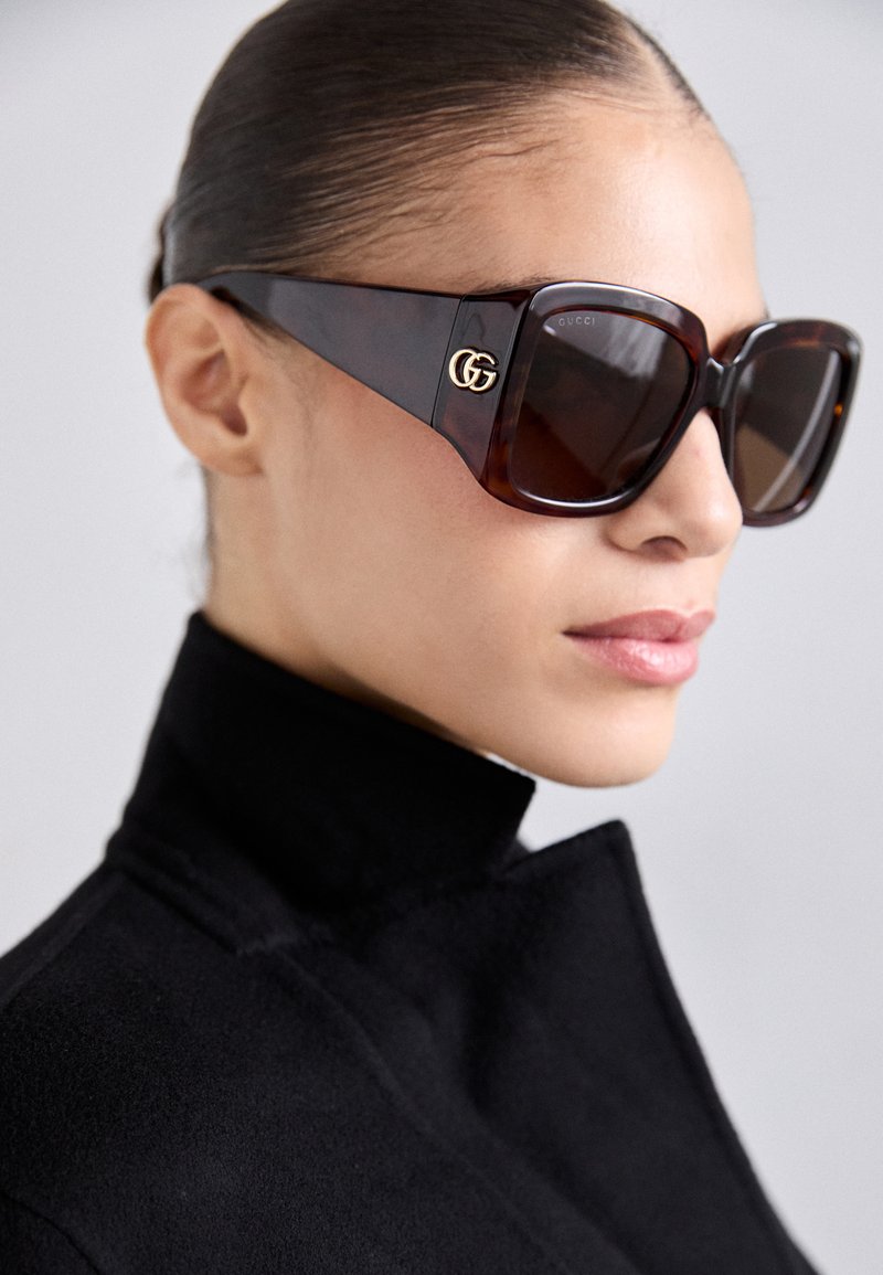 Γυαλιά ηλίου με υπερμεγέθη καφέ καβουρδισμένα πλαίσια, σκούρους φακούς και χρυσά λογότυπα GG στα πλάγια. Λείο, γυαλιστερό φινίρισμα.