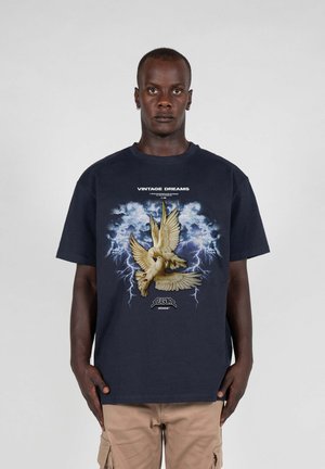 Marineblå bomulds t-shirt med et grafisk motiv af en gul due med udbredte vinger, sat mod en stormfuld baggrund med lyn.