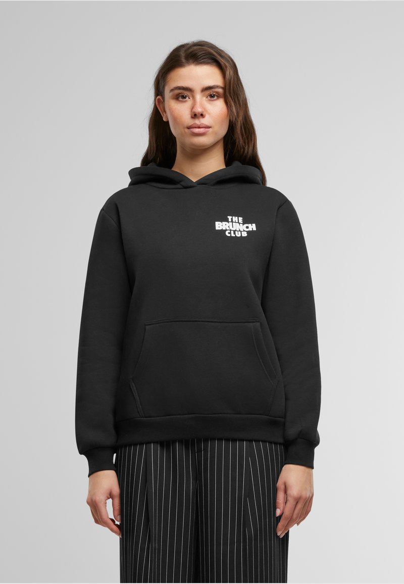 Black hoodie made from soft material, featuring a front pocket and a drawstring hood. "THE BRUNCH CLUB" is printed in white on the chest.