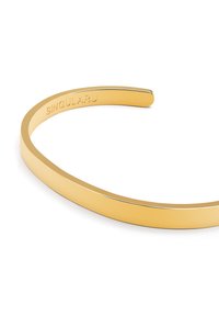 Bracciale a cuffia in metallo tono oro con superficie liscia e lucida. Presenta un design semplice e curvo. Iscrizioni sulla parte interna.