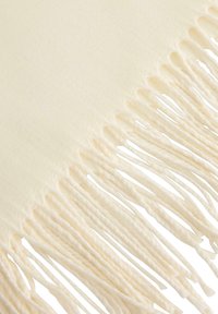 Kremowy szalik z frędzlami o gładkiej, miękkiej fakturze i równomiernie rozmieszczonymi, skręconymi frędzlami na jednym z brzegów. Lekki i uniwersalny design.