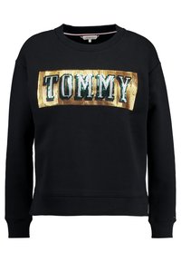 Czarna bluza z okrągłym dekoltem, z przodu ozdobiona złoto-zielonym cekinowym logo "TOMMY". Mankiety i dół bluzy wykończone ściągaczem. Miękki materiał.