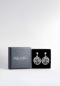 Orecchini in argento a forma di albero della vita, dal design circolare, con intricati motivi a ritaglio, presentati in una scatola regalo rivestita in velluto nero.