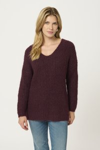 V-Ausschnitt, langärmliger Pullover in tiefem Burgunderrot, aus strukturiertem Strickstoff, mit lockerer Passform und Ripp-Details. Kombiniert mit hellen Jeans.