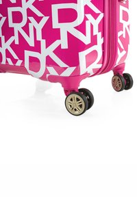 Maleta rígida rosa con grandes letras blancas "RY", acabado liso y ruedas con acentos dorados para mayor movilidad. Diseño con cremallera en la parte superior.