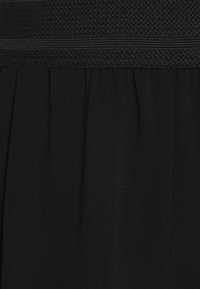 Schwarze Rock mit einem strukturierten, elastischen Bund und weichem Stoff. Das plissierte Design ermöglicht fließende Bewegungen und Komfort.