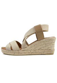 Wedge sandal with beige textile upper, overlapping straps, and a jute-wrapped platform. Features a soft footbed and rubber outsole.