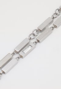 Bracciale in metallo argento composto da anelli rettangolari, con finiture lucide e spazzolate, dotato di una pietra rettangolare trasparente e incisione "Calvin Klein".