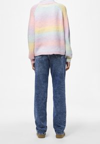 Pull rayé pastel en tissu tricoté doux, doté d'un col montant et de manches raglan, associé à un jean bleu coupe décontractée et des chaussures marron clair.