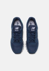 Pair of navy blue New Balance 500 sneakers with mesh and leather details, white midsoles, and black rubber outsoles, viewed from above.