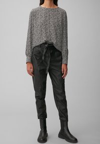 Maglia a maniche lunghe a righe bianche e nere abbinata a pantaloni in ecopelle neri a vita alta e stivaletti neri.