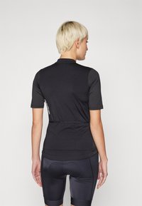 Svart cykeltröja med korta ärmar, tillverkad av en slät tyg, med en dragkedja vid kragen, diskret logotyp och en slim fit design.
