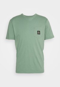 Kortärmad, mintgrön t-shirt i mjuk bomull. Har en bröstficka med en svart etikett och enkla sömnadsdetaljer.