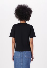 Camiseta negra de manga corta con cuello redondo, hecha de algodón, con un corte relajado y una textura lisa y uniforme.