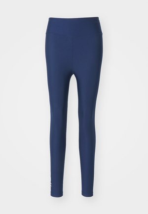 Navy blue leggings made of stretchy fabric with a high waistband and smooth texture. Features a small logo detail near the ankle.