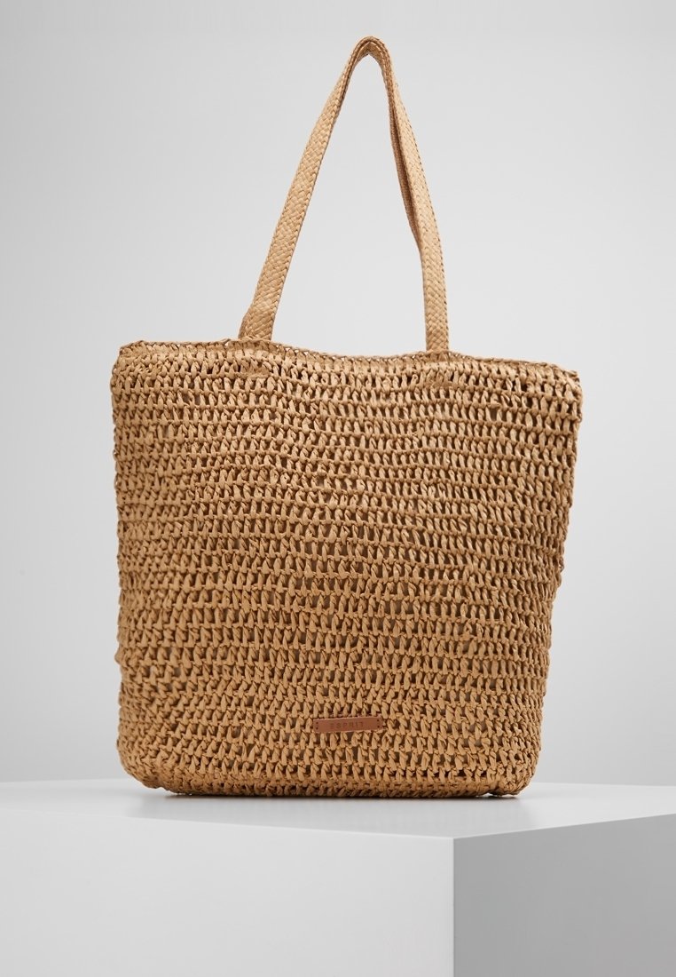 Vävt halm totebag i naturlig färg. Har två axelremmar och en rektangulär form med en strukturerad yta. Läderetikett fäst.
