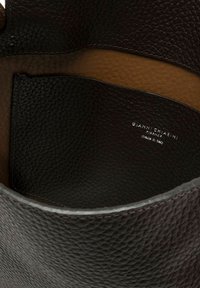 Interno di una borsa in pelle nera con sezioni in marrone scuro testurizzato e in tan liscio. Presenta il marchio impresso "GIANNI CHIARINI, made in Italy."