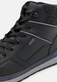 Zwarte leren hoge schoen met een gestructureerde grijs stoffen kraag, metalen vetertjes en een subtiel logo, voorzien van donkere veters en een gevoerde tussenzool.