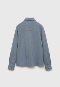 Light blue button-up shirt, textured fabric, long sleeves with button accents, back yoke detail, and straight hem. Classic collar design.