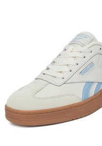 Balti ir šviesiai mėlyni Reebok sportbačiai su baltais raišteliais ir tan spalvos guminiais padais, rodantys priekinį ir šoninį vaizdą.