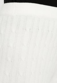 Pulover alb cu model tricotat în cablu, cu guler rotund cu dungi și un model texturat. Material moale cu un design voluminos și reliefat.