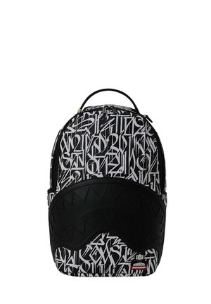 Zaino bianco e nero con scritte astratte in stile graffiti e un pannello nero che ricorda denti appuntiti sul davanti.