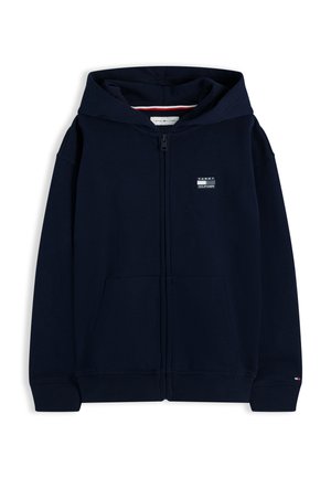 Μπλε ναυτικό φούτερ με φερμουάρ, μπροστινές τσέπες, πλεκτές μανσέτες και τελείωμα, λογότυπο Tommy Hilfiger στο στήθος και μικρή σημαία στη μανσέτα του μανικιού.