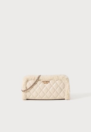 Crèmekleurige doorgestikte handtas met bontafwerking, gouden "GUESS" logo en een zilveren kettingriem tegen een effen witte achtergrond.