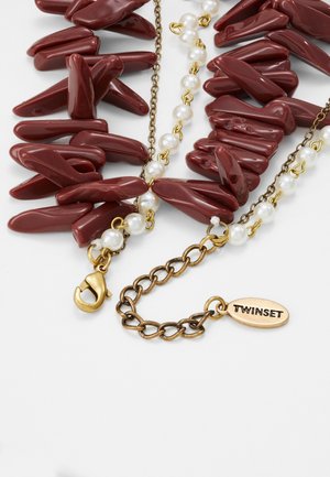 Guld halskæde med uregelmæssige mørkerøde koral-lignende perler, små hvide perler, lås med hummerlås og ovalt mærke med indgraveringen "TWINSET."