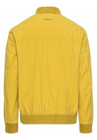 Leichte gelbe Jacke mit einem gerippten Kragen, elastischen Bündchen und einer glatten Textur. Die Rückseite hat ein Logo-Detail in der Nähe des Ausschnitts.
