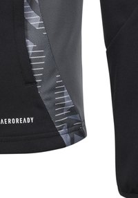Schwarzshirt für Sport mit einem strukturierten grauen Panel, das abstrakte Muster und weiße Streifen aufweist, mit dem Markennamen "AEROREADY" unten links.