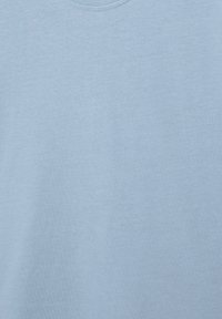 Tessuto di cotone azzurro chiaro con trama fine visibile e cuciture vicino al bordo superiore, che mostrano texture e morbidezza.