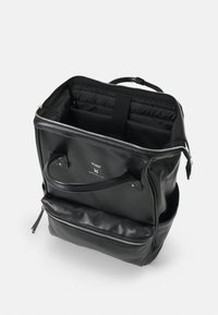 Mochila de cuero negra con abertura con cremallera, asa superior y bolsillo frontal externo. El interior cuenta con un forro de tela y bolsillos organizadores.