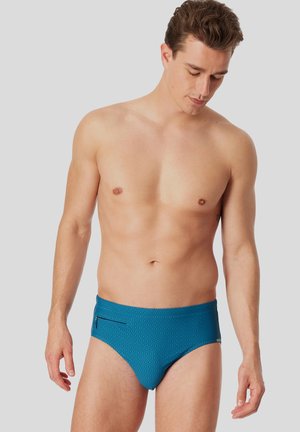 Herren-Schwimmbriefe in Teal mit einem dezenten gepunkteten Muster, ausgestattet mit einer Reißverschlusstasche an der Seite und einem glatten, dehnbaren Stoff.