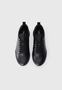 Zwarte leren sneakers met een gladde textuur, featuring afgeronde neuzen, vetersluiting en aanhaalbare lipjes aan de hiel voor eenvoudig aan- en uittrekken.