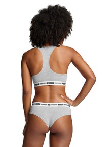 Grijze sportbh met racerback ontwerp en elastische band met zwarte "PUMA" branding. Bijpassende grijze hipsteronderbroek met vergelijkbare branding.