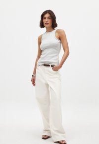 Top sans manches gris clair en coton, associé à un pantalon blanc ample. Une ceinture marron accentue la taille. Design simple, look décontracté.