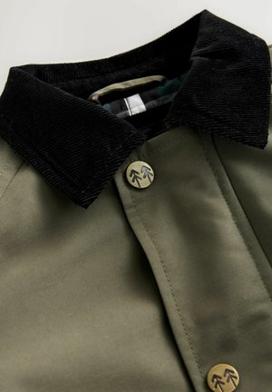 Baumwollhemdjacke in Olivgrün mit einem schwarzen Cordkragen. Verfügt über einen runden Metallknopf mit Pfeilmotiv und sichtbare Nähdetails.