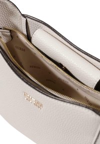 Borsa a tracolla grigio chiaro con texture e accessori in oro, dotata di chiusura con zip, scomparti interni e logo stampato sulla fodera.