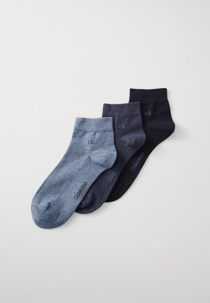 Calvin Klein ankelstrømper i tre farver: lysegrå, mørkegrå og marineblå. Lavet af blødt stof med ribbet kant og logo nær anklen.
