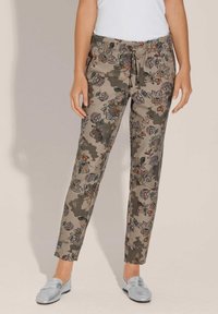 Blumengemusterte Jogginghosen in gedämpftem Taupe, mit einem Kordelzugbund und Knöchelbündchen, kombiniert mit hellsilbernen Loafern.