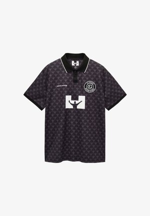 Schwarzes Poloshirt mit geometrischem Muster, kontrastierendem weißen Kragen und einer zentralen Grafik mit einer Silhouette und Text.